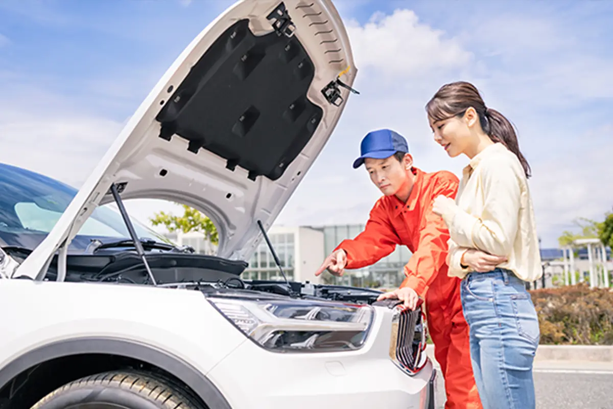 エンジンルームを整備する男性と説明を聞く女性